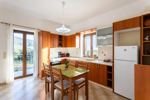 a kitchen with a table and a refrigerator at Mani Stone Villa Majlinda - Tranquil Getaway Gem in Riglia