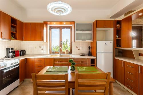 a kitchen with wooden cabinets and a table with chairs at Mani Stone Villa Majlinda - Tranquil Getaway Gem in Riglia