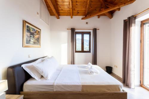 a bedroom with a large bed with white sheets at Mani Stone Villa Majlinda - Tranquil Getaway Gem in Riglia