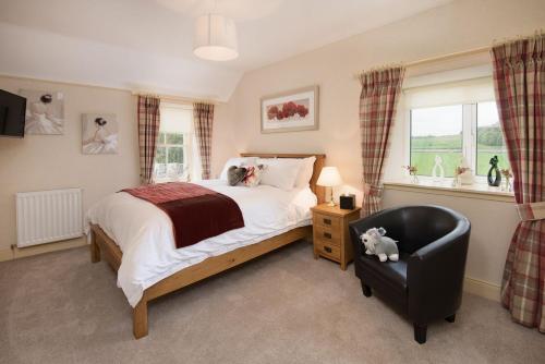 a bedroom with a bed and a chair and a window at Dryburgh Stirling Two in Saint Boswells