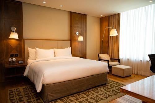 a bedroom with a large white bed and a chair at DoubleTree by Hilton-Pune Chinchwad in Pune