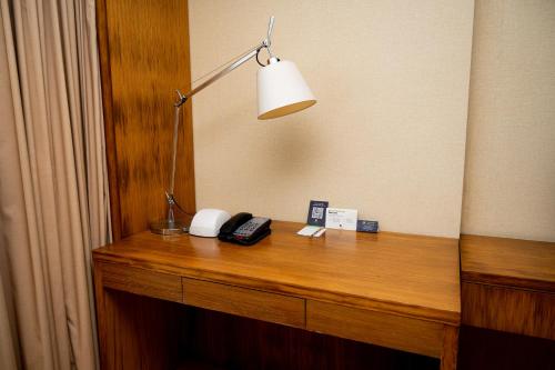 a desk in a hotel room with a lamp and a telephone at DoubleTree by Hilton-Pune Chinchwad in Pune
