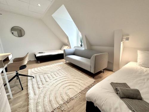 a bedroom with a bed and a couch and a chair at Attic Living Hostel in Borås