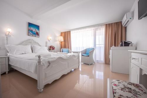 a white bedroom with a bed and two chairs at SunRise in Venus