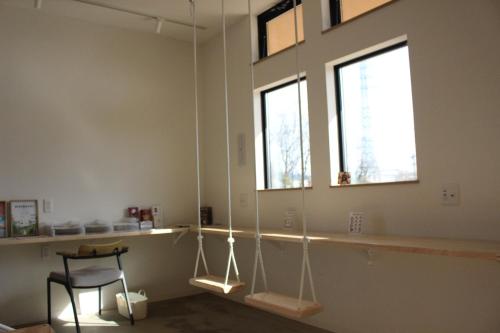 a room with a chair and two windows at Matoi Hostel & Bar in Takasaki