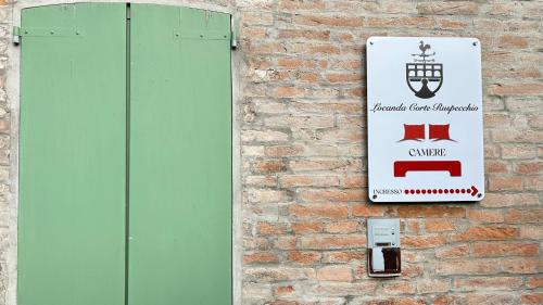 a sign on the side of a brick wall at Locanda Corte Ruspecchio in Quattro Castella