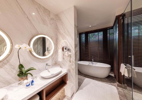 Sunway Resort Hotel في كوالالمبور: حمام مع حوض ومغسلة ومرآة