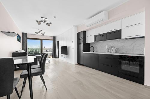 a kitchen and dining room with a table and chairs at Solaris Darłówko Premium Emilia Strupiechowska in Darłowo