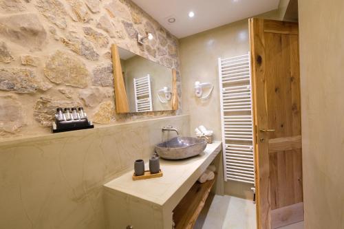 a bathroom with a sink and a stone wall at Dryas Guesthouse in Polydrossos
