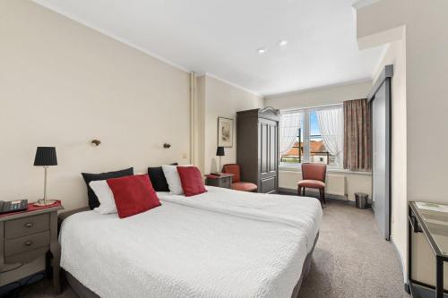 1 dormitorio con 1 cama blanca grande con almohadas rojas en Gillis Eight by Romy&Travis, en Brujas