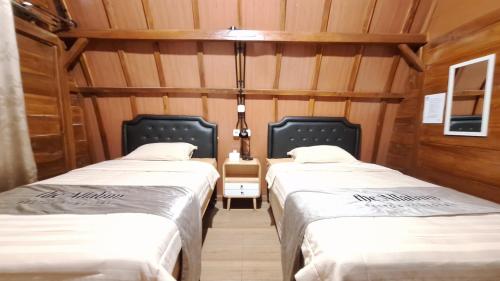 two twin beds in a room with wooden walls at The Allabun Glamping Yogyakarta in Kaliurang