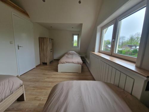 1 dormitorio con 2 camas y ventana en Ruim vakantiehuis, rustig gelegen in Bruinisse, en Bruinisse