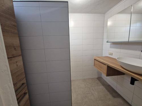 baño con paredes de azulejos blancos y lavabo en Ruim vakantiehuis, rustig gelegen in Bruinisse, en Bruinisse