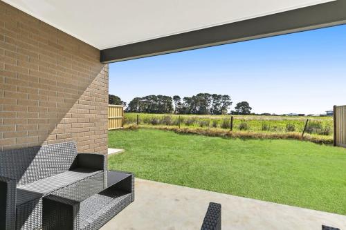 a patio with a bench and a grass yard at Brand new House close to shops in Dunes estate in Torquay