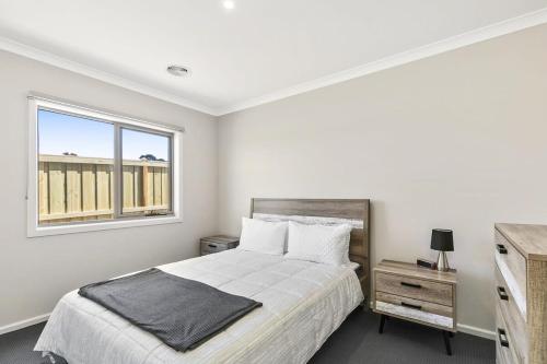 Habitación blanca con cama y ventana en Brand new House close to shops in Dunes estate en Torquay