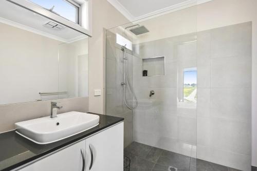 y baño blanco con lavabo y ducha. en Brand new House close to shops in Dunes estate en Torquay