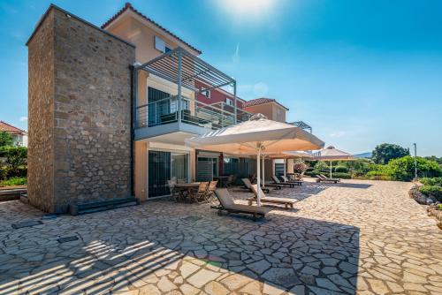 a patio with chairs and umbrellas in front of a building at Dialiskari Villas in Marathopolis