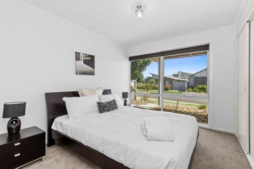 a bedroom with a large bed and a large window at Half Moon Bay Hideaway 1 min to Foreshore in Indented Head