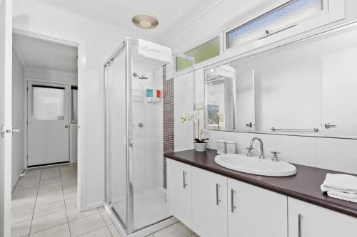 a white bathroom with a sink and a shower at Half Moon Bay Hideaway 1 min to Foreshore in Indented Head