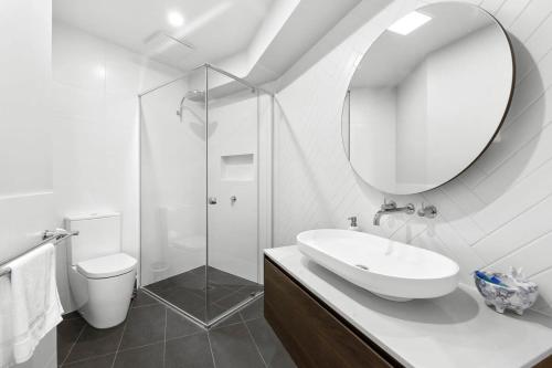 ein weißes Badezimmer mit einem Waschbecken und einem Spiegel in der Unterkunft Brand New Townhouse Coastal Lifestyle Torquay in Torquay