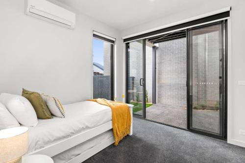 Schlafzimmer mit einem Bett und Glasschiebetüren in der Unterkunft Brand New Townhouse Coastal Lifestyle Torquay in Torquay