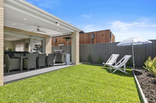 a backyard with lawn chairs and an umbrella at Hampton's Getaway in Torquay in Torquay