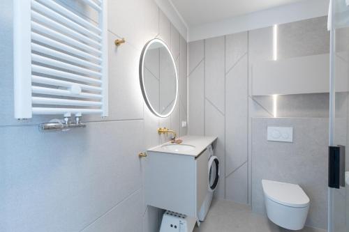 a white bathroom with a toilet and a mirror at HEVENIA POGORZELICA - APARTAMENT 2 in Pogorzelica