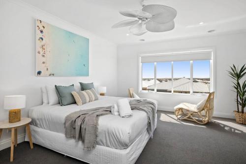 een witte slaapkamer met een bed en een raam bij Seaspray Ocean View Retreat in Torquay