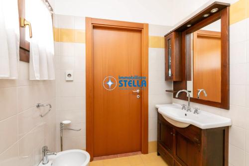 bagno con lavabo e servizi igienici e porta in legno di Foresteria Golf a Jesolo