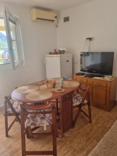 um quarto com uma mesa e uma televisão e uma mesa e cadeiras em Apartment Jelena em Kotor