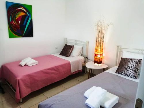 Stamatopoulaíika的住宿－Lakkopetra Sunrise，一间卧室设有两张床和一张桌子上的台灯。