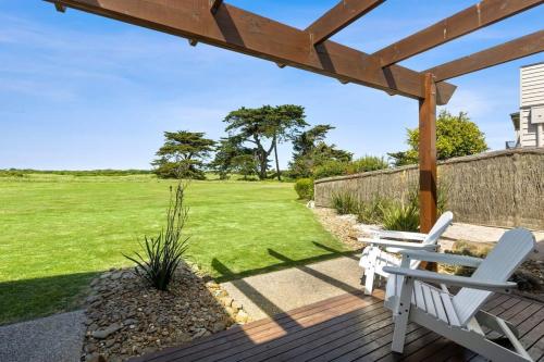 a patio with two white chairs on a wooden deck at Beach and Golf Haven With Spa Luxury Living in Connewarre