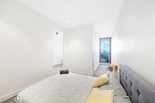 biała sypialnia z łóżkiem i kanapą w obiekcie A Stylish & Cozy 2BR Apt Near Melbourne Central w Melbourne