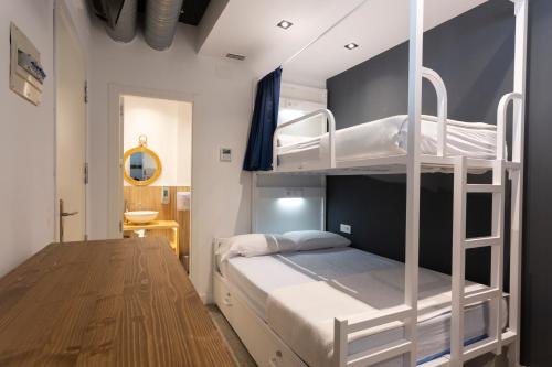 a bedroom with two bunk beds and a desk at Malaga Stop Hostel AB in Málaga