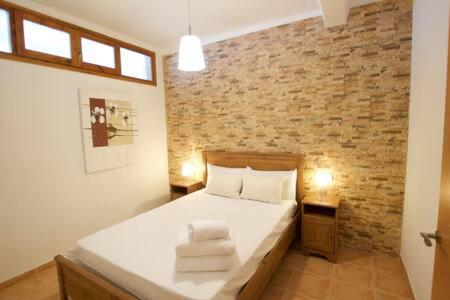 sypialnia z białym łóżkiem z ceglaną ścianą w obiekcie Apartament Boix petit w mieście La Molina