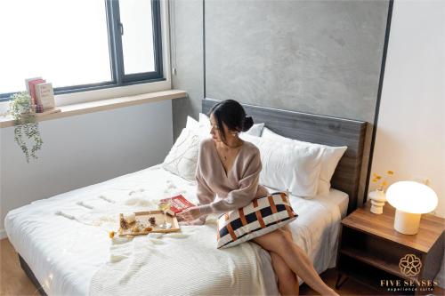 una mujer sentada en una cama leyendo un libro en Chambers Kuala Lumpur by Five Senses, en Kuala Lumpur