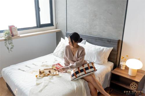 a woman sitting on a bed reading a book at Chambers Kuala Lumpur by Five Senses in Kuala Lumpur
