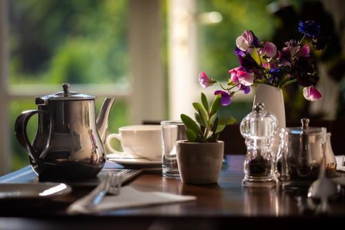 a table with a tea kettle and a vase of flowers at Broom House at Egton Bridge in Egton