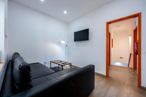 a living room with a black couch and a flat screen tv at The Macarena Beach Hostel in Lagos