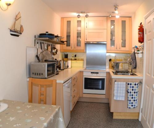 a kitchen with wooden cabinets and white appliances at Seaview at Merton Hall Dinas Cross in Dinas