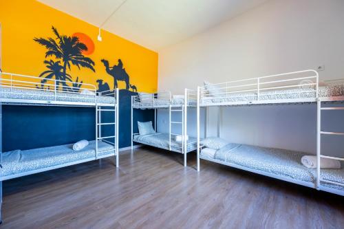 a room with three bunk beds and a yellow wall at The Macarena Beach Hostel in Lagos