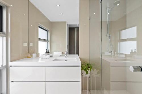 a white bathroom with a sink and a shower at Whitewash Beachfront Apartment on The Esplanade in Torquay
