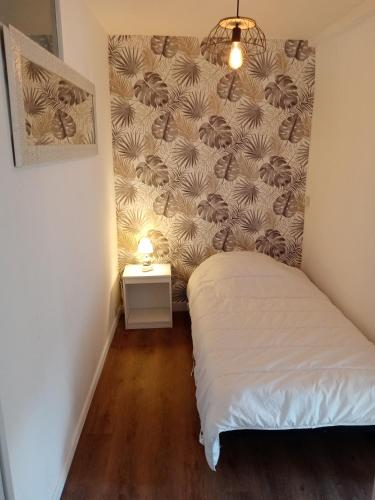 ein kleines Schlafzimmer mit einem Bett und einer Wand in der Unterkunft Appartement centre ville in Vimoutiers