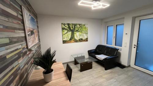 a living room with a black leather couch and a table at Gemütlich, ländlich, stadtnah in Stutensee