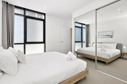 um quarto branco com 2 camas e um espelho em Urban Executive Style Meets Relaxed Coastal Vibes em Ocean Grove