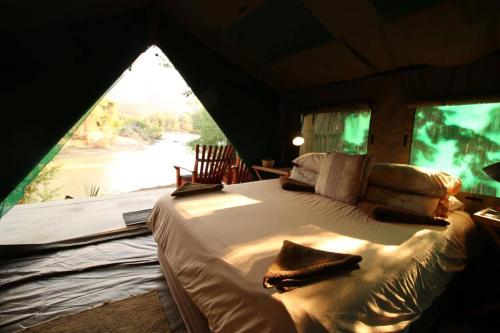 a bedroom with a bed in a tent with a window at Epupa Camp in Epupa