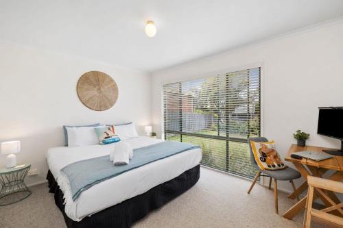 1 dormitorio con cama, escritorio y ventana en Jan Juc Ocean Views And Sunshine en Torquay