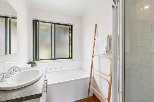 La salle de bains blanche est pourvue d'un lavabo et d'une baignoire. dans l'établissement Jan Juc Ocean Views And Sunshine, à Torquay