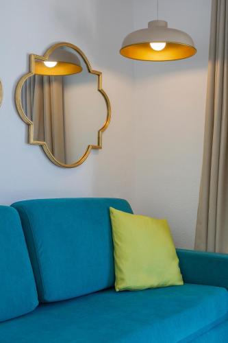 a blue couch with a yellow pillow and a mirror at Flipflop Surfing Playa in Santa Ponsa