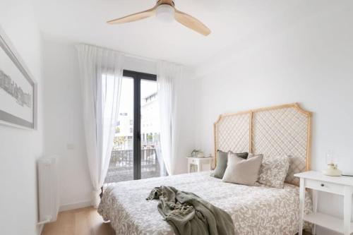 a white bedroom with a bed and a ceiling fan at Apartamento La Nuez by Clabao in Pamplona